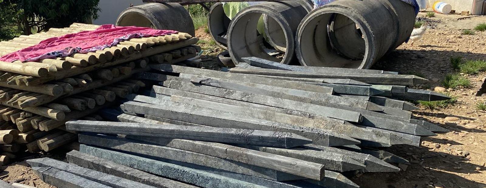 Estantillos y postes acopiados en una finca del piedemonte, con la cordillera al fondo.