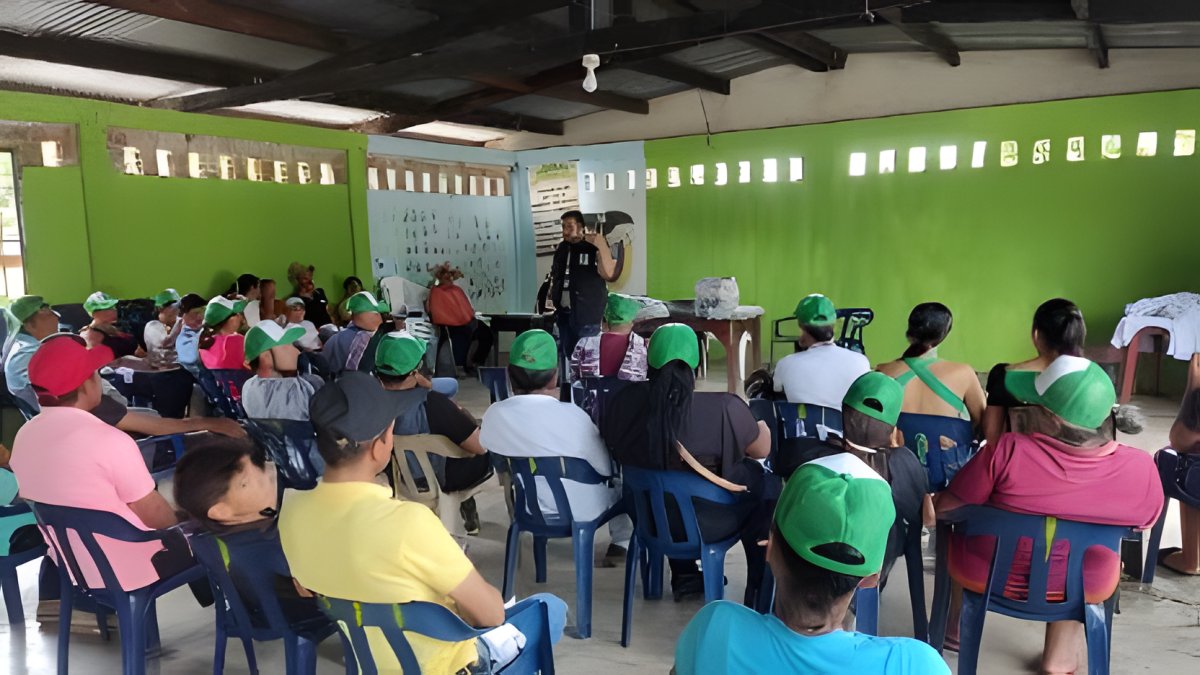 Asistentes con gorras verdes llenan un salón comunal durante una jornada de la Cátedra Ambiental.