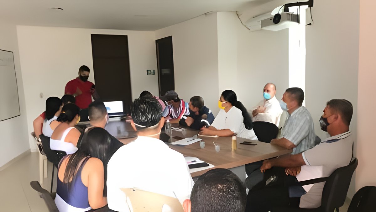 Una reunión de trabajo alrededor de una mesa de juntas en una sala institucional.