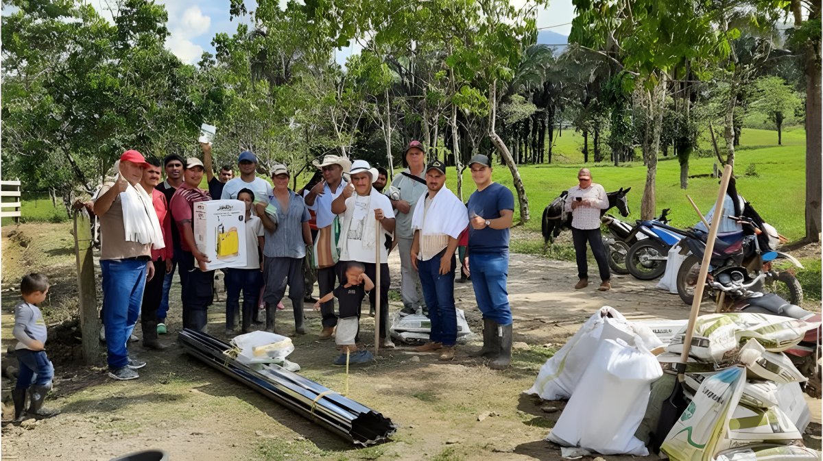 Un grupo de campesinos posa en el campo junto a los materiales y los insumos entregados.
